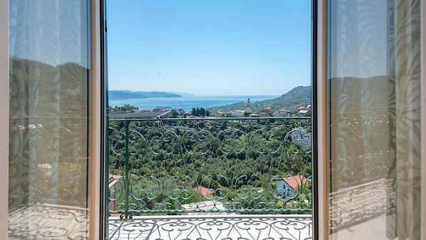Ein Balkon mit Blick auf eine Küstenlandschaft, einschließlich Hügeln und einer entfernten Wasserfläche.