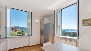 Eine moderne Küche mit großen Fenstern, einem Kühlschrank und Blick ins Grüne.