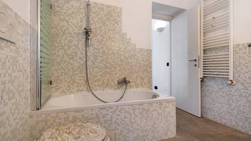 Une salle de bain avec une baignoire, une douche et des toilettes.