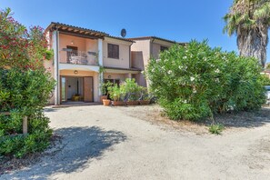 Une maison à deux étages avec un balcon, des plantes en pot et une allée gravillonnée.