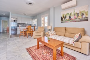 A living room with a sofa, coffee table, and a dining area with chairs and a table.