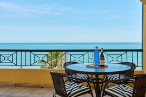 Ein runder Tisch mit Stühlen auf einem Balkon mit Blick auf das Meer.