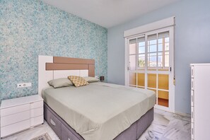Ein Schlafzimmer mit einem Bett, einem Nachttisch, einer Kommode, einem Fenster mit Aussicht und einer Tür.