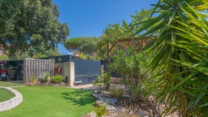 Un jardín con césped, una valla de madera y diversas plantas.