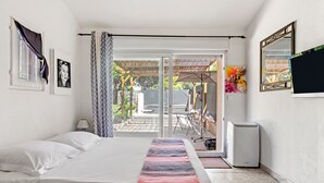 Un dormitorio con cama, televisor, calefacción y puerta corrediza a un patio.
