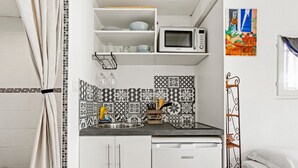 Una cocina compacta con microondas, lavamanos y salpicadero decorado.