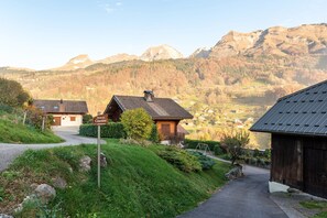A rural mountain village with traditional wooden houses, a clear path leading through the village, and a sign indicating a cemetery.