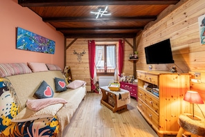 A cozy cabin with a bed, a television, a wooden dresser, and a painting on the wall.