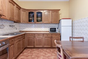 A kitchen with wooden cabinets, a microwave, a refrigerator, and a dining table.
