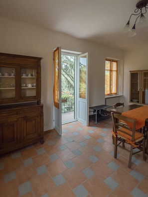 A room with a dining table, chairs, a cabinet, and a door leading to a balcony.