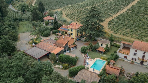 A villa with multiple buildings, a swimming pool, and surrounding greenery.