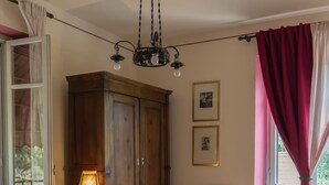 A bedroom with a bed, a wooden wardrobe, a chair, a lamp, and a window with curtains.