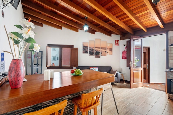 Une cuisine avec un plan de travail en bois, un vase rempli de fleurs et un coin repas comprenant des chaises et un canapé.