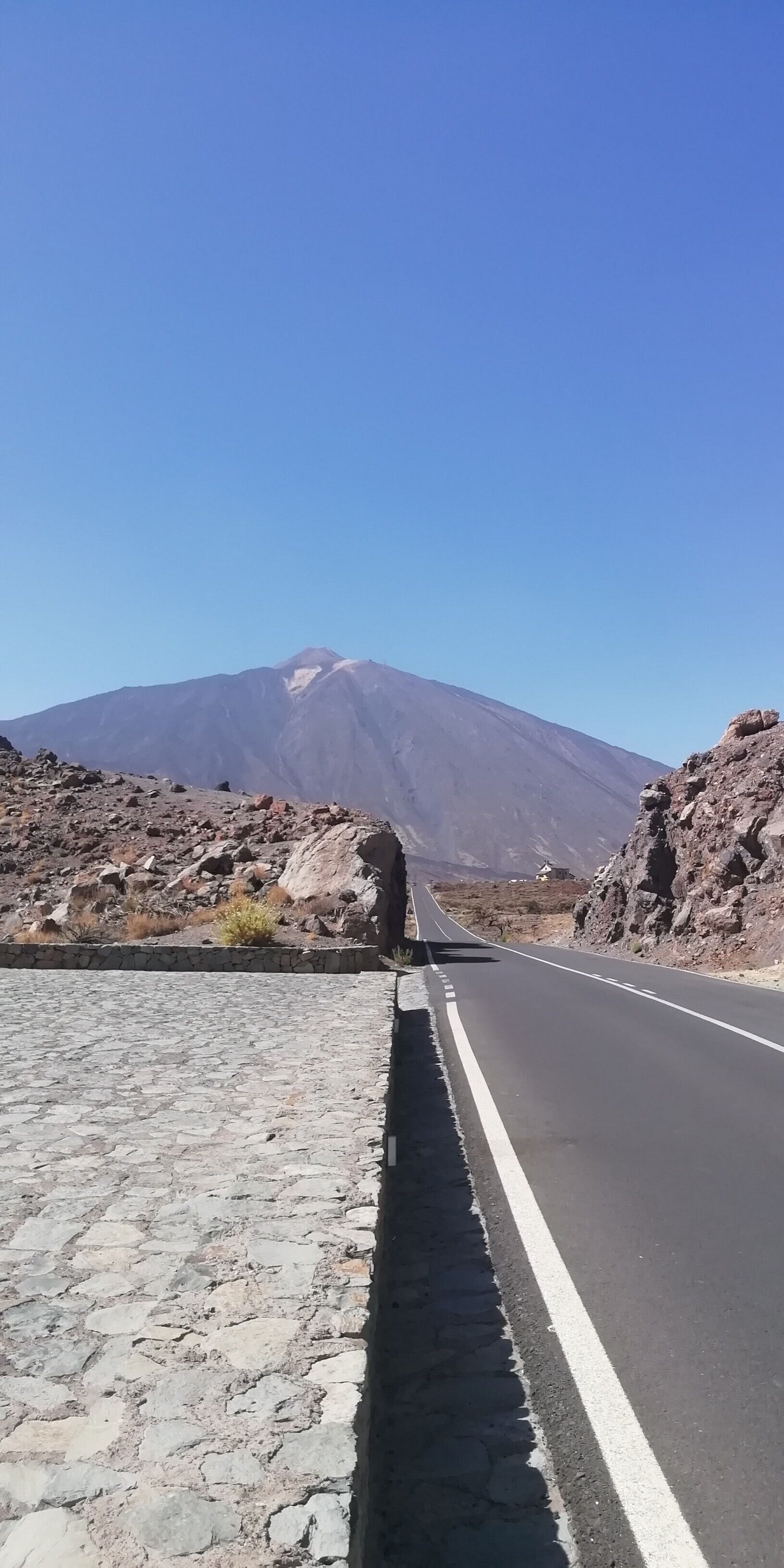 Una carretera pavimentada con una montaña al fondo.
