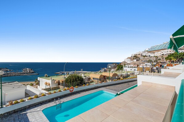 A rooftop pool with a view of the sea and buildings.