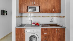 A kitchen with wooden cabinets, a microwave, a washing machine, and a sink. - Vacation Apartment 'Calipso Sun and Beach' with Sea View, Wi-Fi and Air Conditioning (Puertorico)