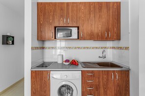 A kitchen with wooden cabinets, a microwave, a washing machine, and a sink. - Vacation Apartment 'Calipso Sun and Beach' with Sea View, Wi-Fi and Air Conditioning (Puertorico)