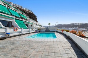 Zona de piscina con vista despejada a la ciudad y montañas al fondo.