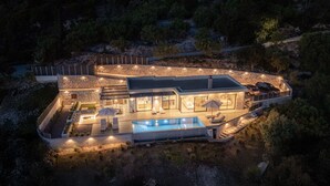 Luchtbeeld van een modern huis met zwembad, terras en een gevel van natuursteen.