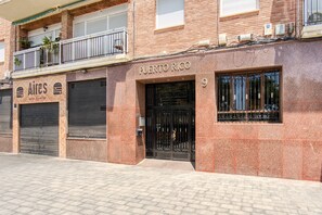 Ein Gebäude mit geschlossenem Rollo auf der linken Seite, einem Schild mit der Aufschrift 'PUERTO RICO' über der Tür und einem Balkon mit Pflanzen.