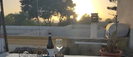 A balcony with potted plants, a bottle, and a glass.