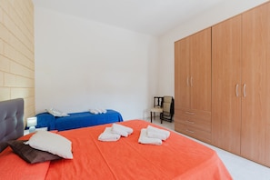A hotel room with a bed, a wardrobe, a chair, and a small table with a lamp. - Apartment 'Andrea's House Marsala' with Sea View and Private Terrace (Marsala)
