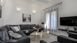 Un salon moderne avec un canapé gris, une table basse, un téléviseur à écran plat et un tableau accroché au mur.