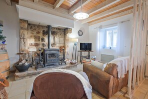 Una sala de estar rústica con una pared de piedra, una chimenea, un sofá, un televisor y un ventanal.