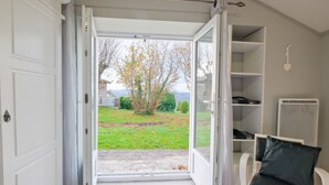 An open door leading to a garden with a view of trees and a lawn. - Gite Le Moutat-La Cave with Private Garden and Wi-Fi (Allemans)