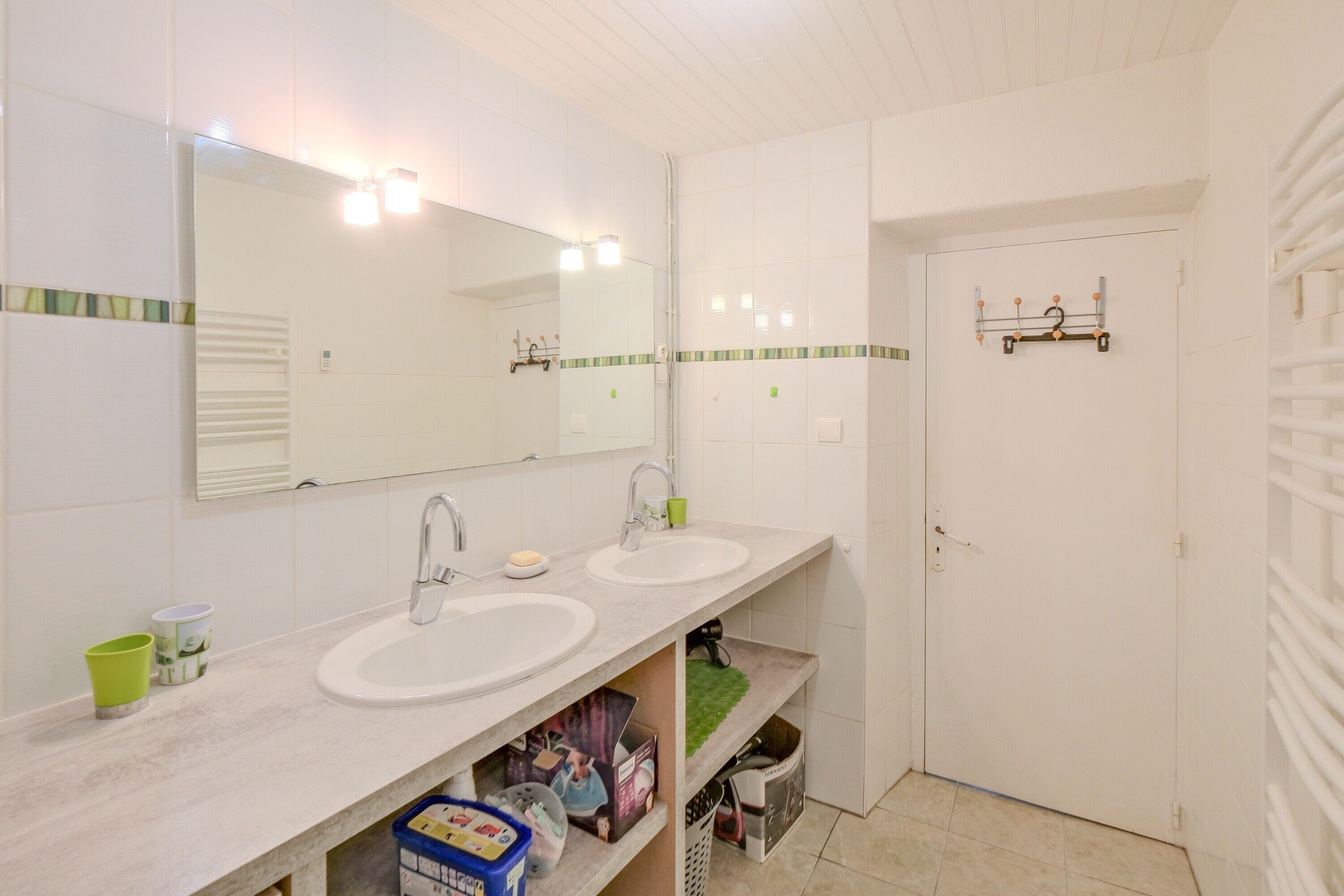 Ein Badezimmer mit zwei Waschbecken, einem Spiegel und einer Tür mit Handtuchhalter.