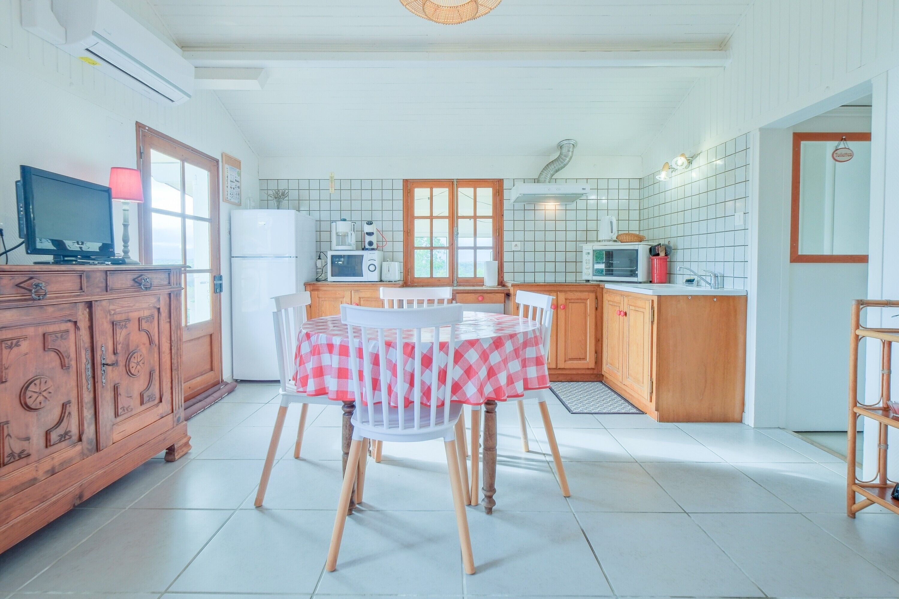 A kitchen with a dining table, chairs, and various appliances.