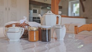 A kitchen with white appliances, a table with various containers, and a wooden chair.