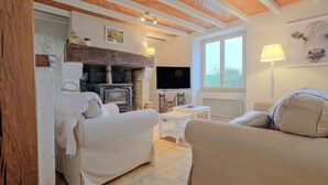 A cozy living room with a fireplace, sofas, a television, and a window.