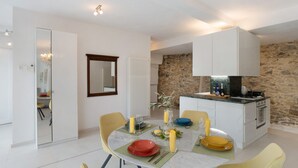 Une cuisine moderne avec un mur en pierre, un meuble blanc et une table à manger décorée de bougies et d’assiettes jaunes.