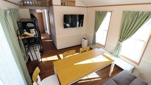 A compact living space with a dining table, chairs, a TV, and a kitchenette.