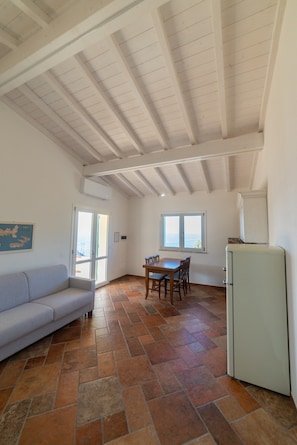 Un vaste espace de vie doté d’un haut plafond, d’une table à manger avec des chaises, d’un canapé et d’un réfrigérateur.