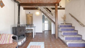 A living area with a fireplace, a dining table, and a staircase. - Holiday Home 'Mora' with Private Terrace, Private Garden and Wi-Fi (Vejer de la Frontera)