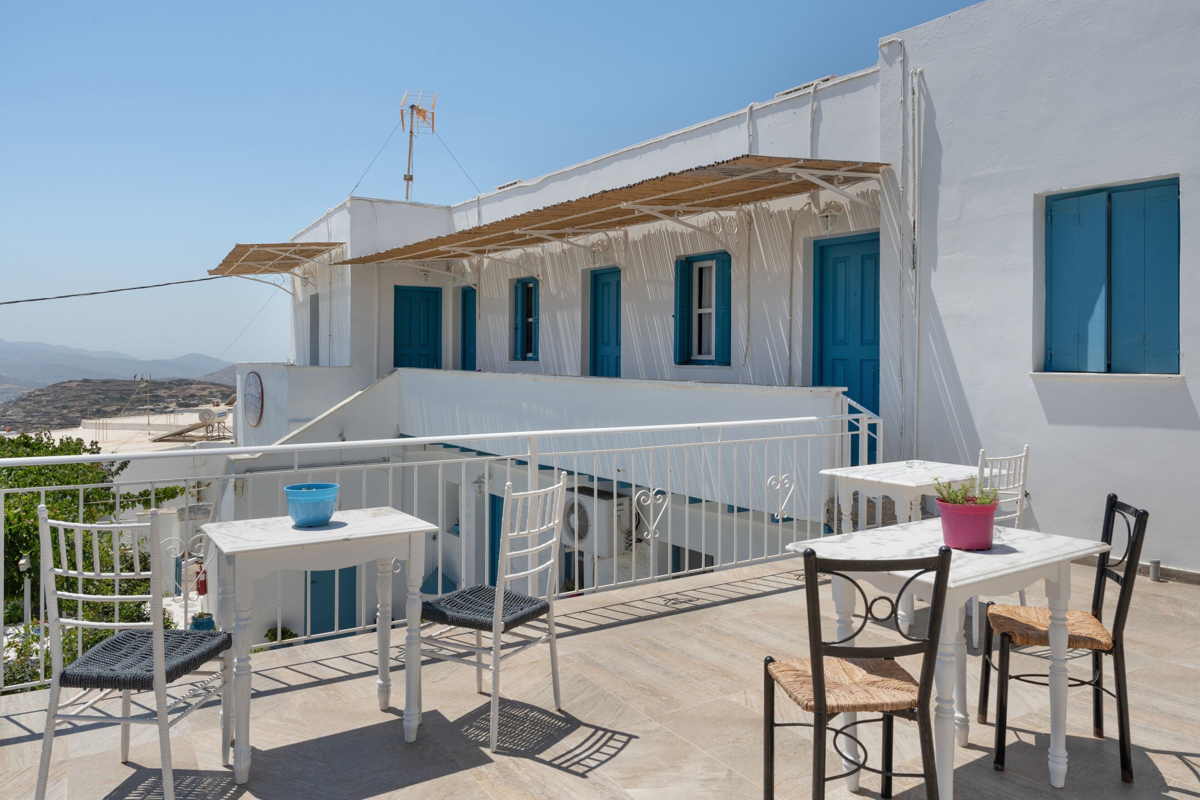 Una terrazza con pareti bianche, persiane blu e un tavolo con sedie.