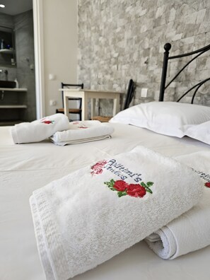 Ein Hotelzimmer mit einem ordentlich bezogenem Bett, einem Nachttisch und einer Wand mit strukturierter Oberfläche.
