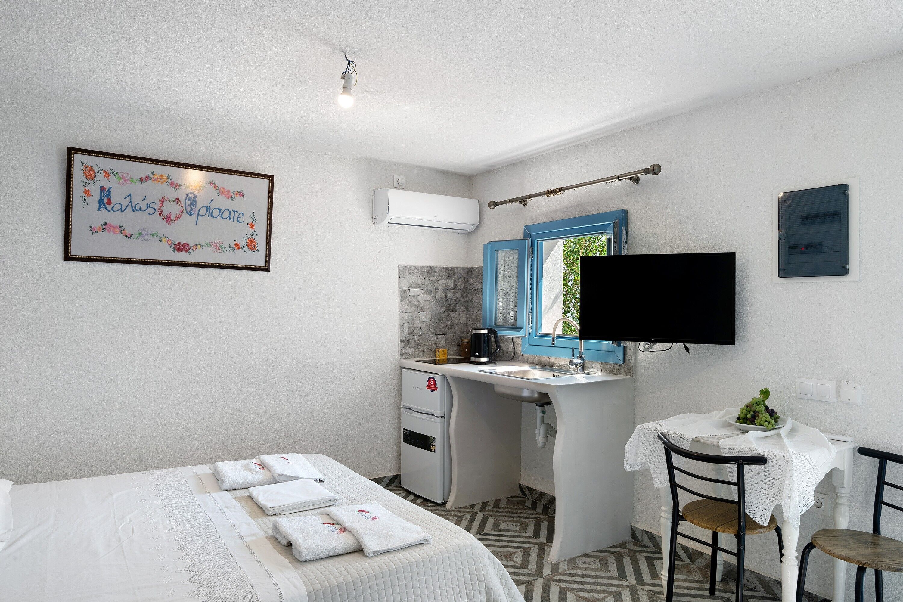 Une chambre d’hôtel avec un lit, un bureau doté d’un lavabo, une télévision et un panneau encadré accroché au mur.