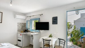 Habitación de hotel con cama, escritorio con computadora, kitchenette pequeña y vista al exterior.