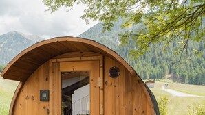 Una cabaña de madera con techo curvo, una puerta con ventana y una ventana pequeña en el lateral.