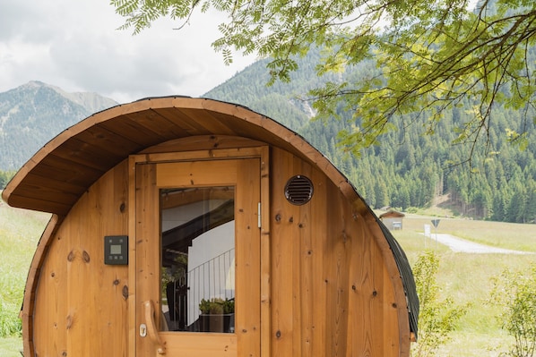 A wooden cabin with a curved roof, a door with a window, and a small window on the side.