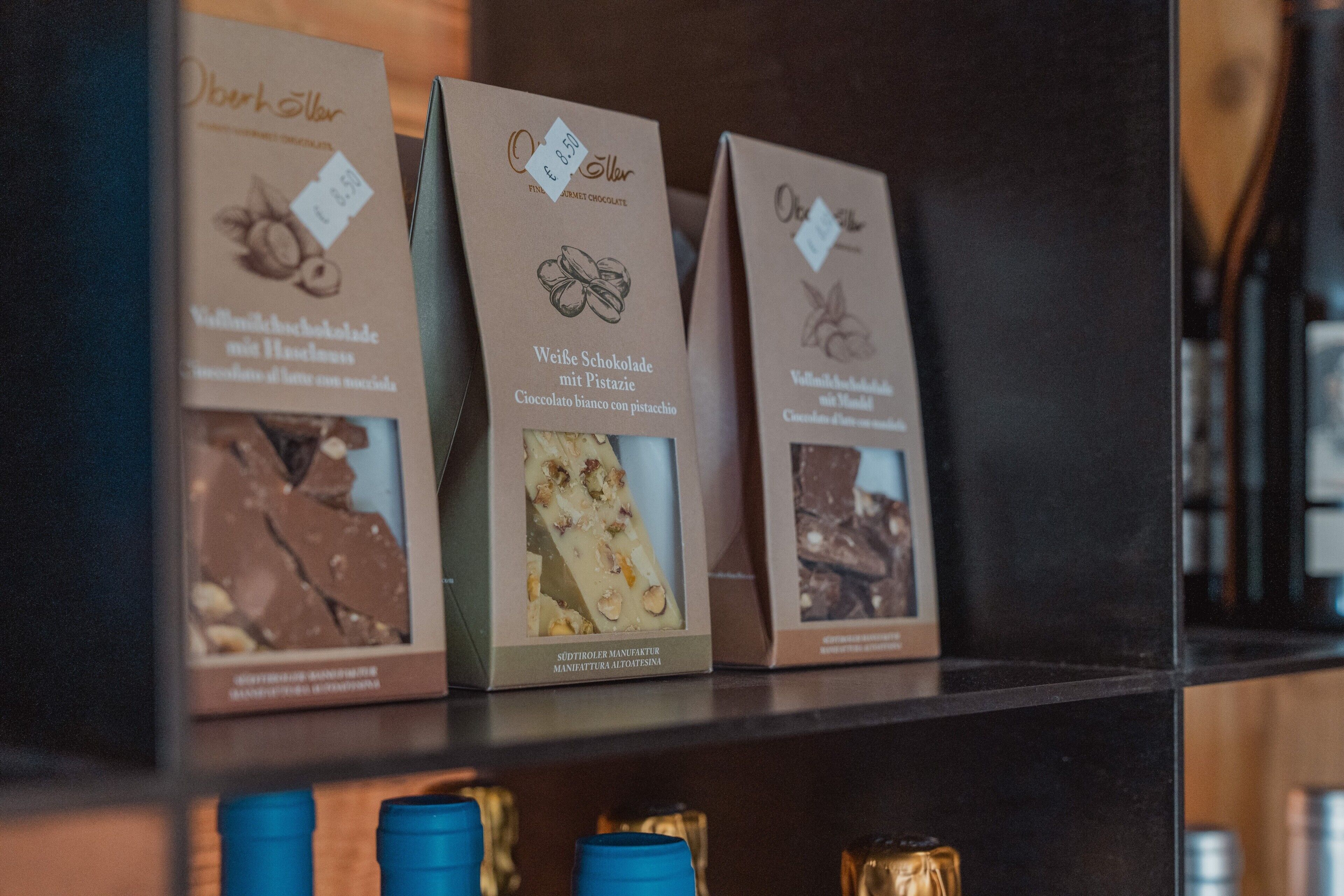 Trois boîtes de chocolats sont présentées sur une étagère, chacune étant munie d’une étiquette indiquant le prix.
