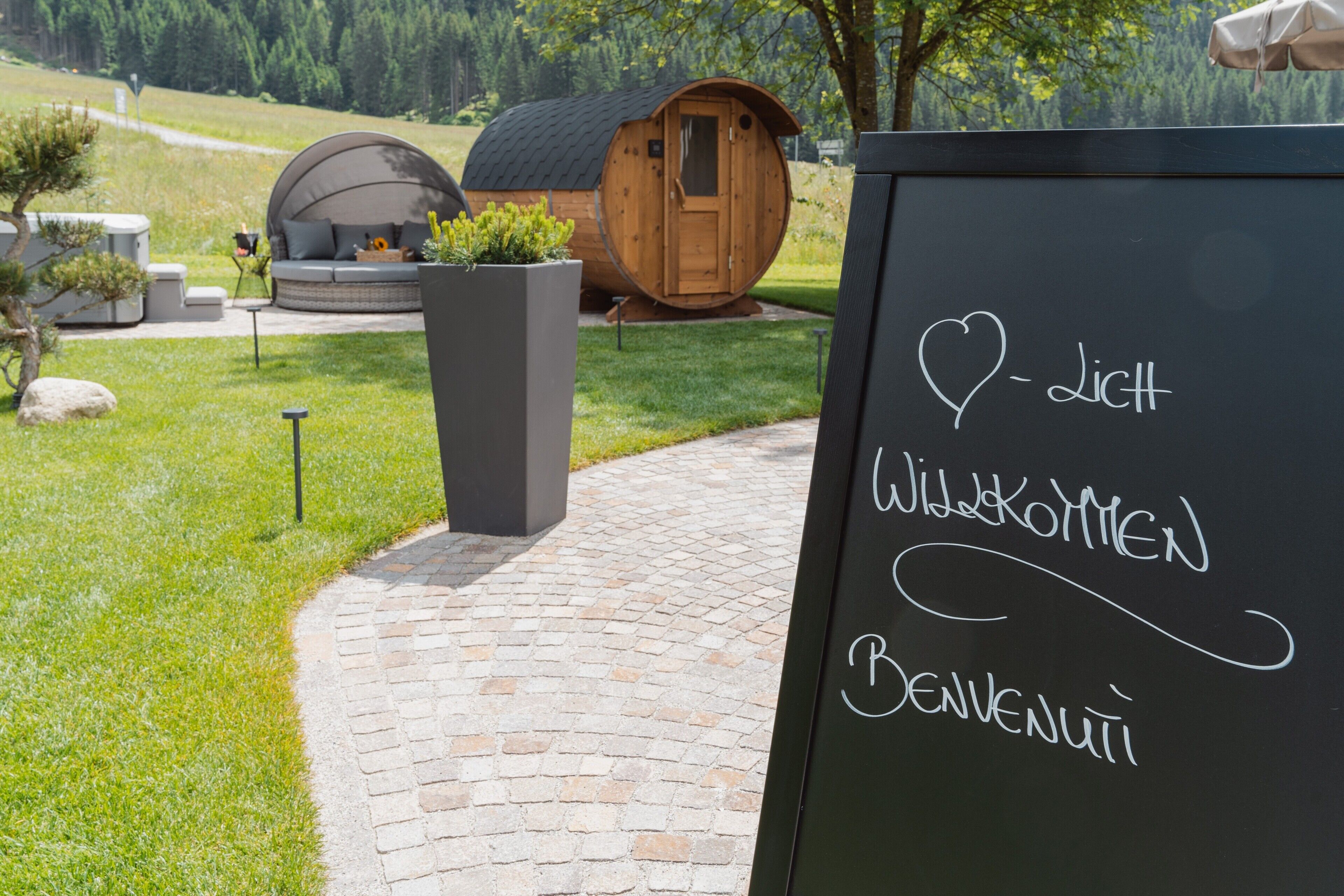 Ein Weinfasshaus mit einer Tafel, auf der 'Welcome' und 'Willkommen' in einer anderen Sprache stehen.