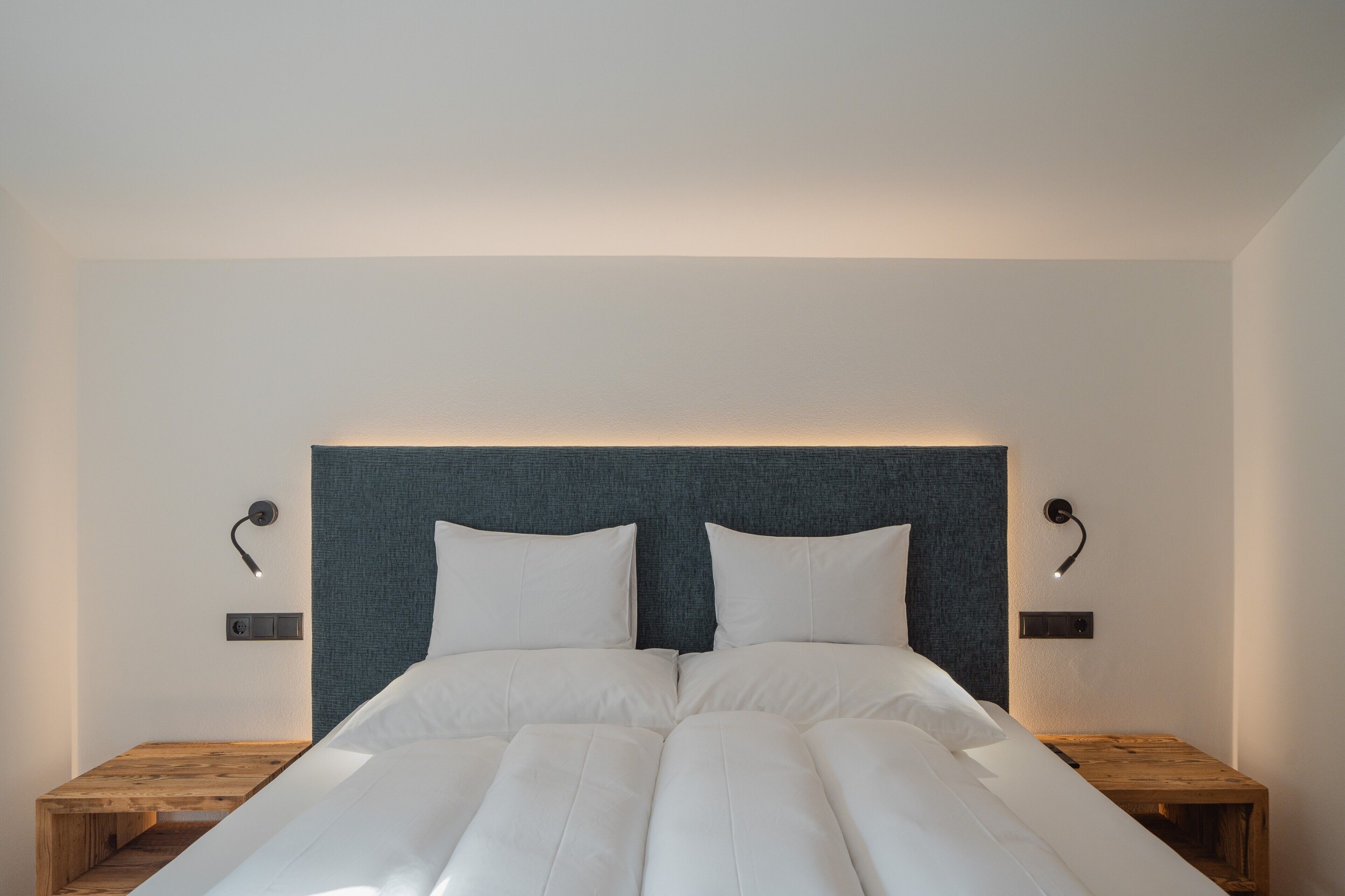Ein modernes Schlafzimmer mit einem großen Bett, Holznachttischen und Wandleuchten.