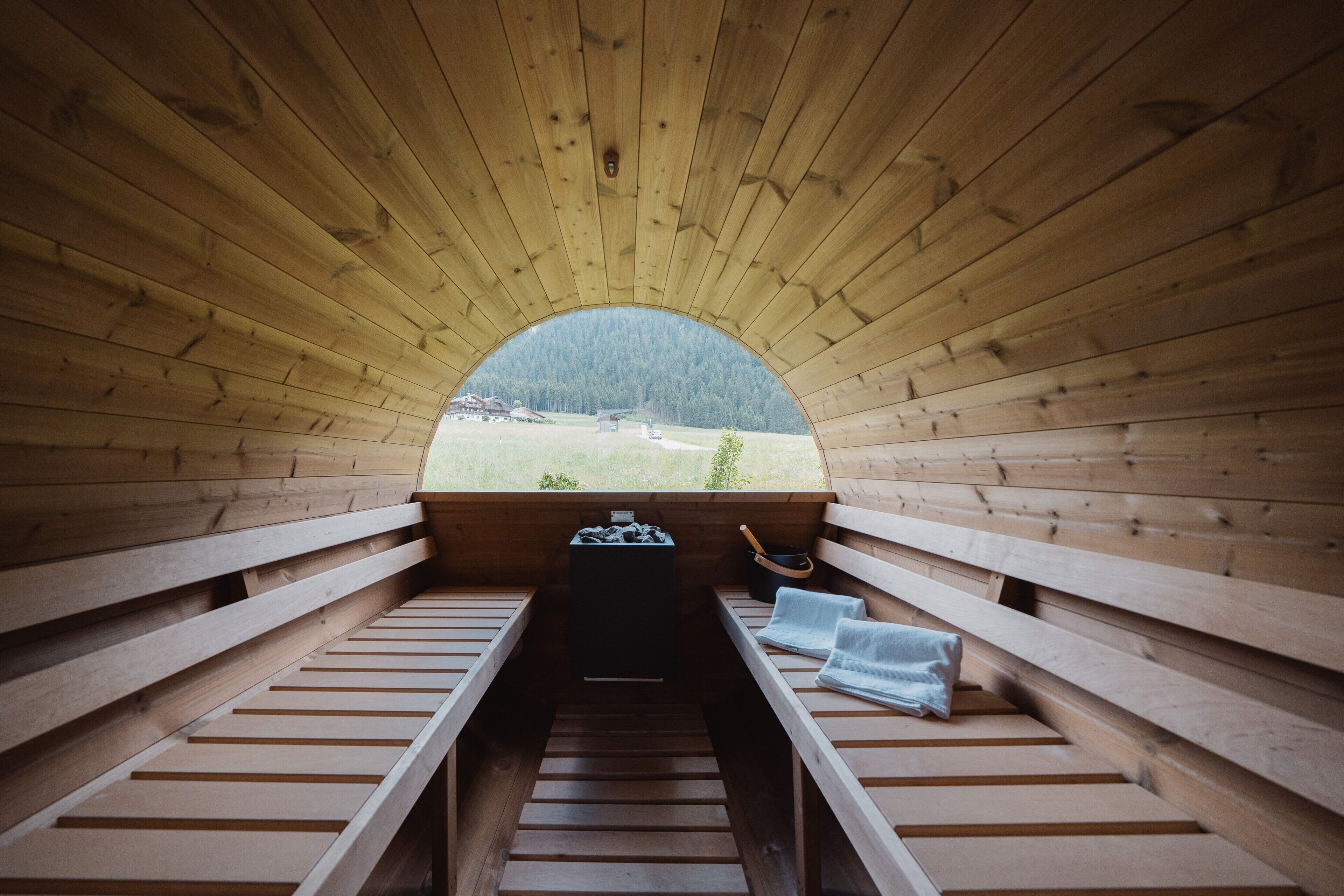 Een sauna met houten banken en uitzicht op een bebost gebied.