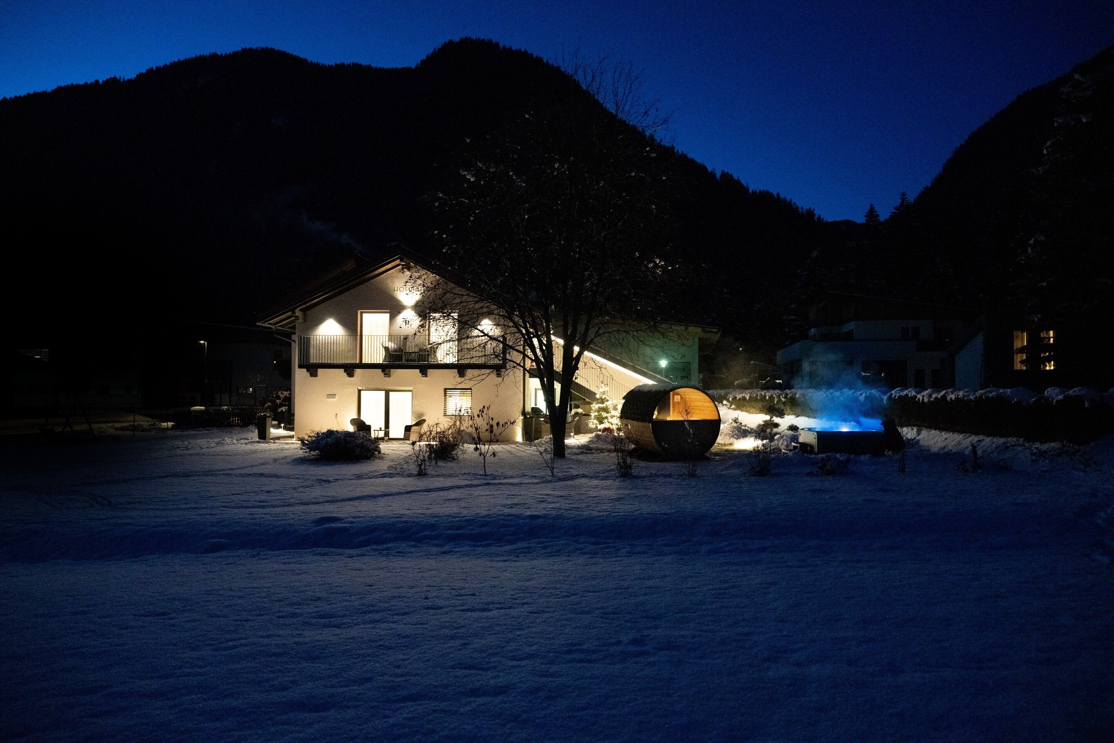 Una casa con un cortile innevato, una grande struttura sferica e una montagna sullo sfondo.