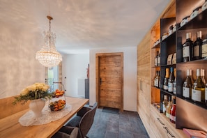 A dining area with a wooden table, a chandelier, a vase with flowers, and a wine rack.