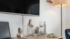 A modern living room with a flat-screen TV, a laptop, a lamp, decorative items, and a chair. - Apartment 'Blue Beach Home' with Terrace (Conil de la Frontera)